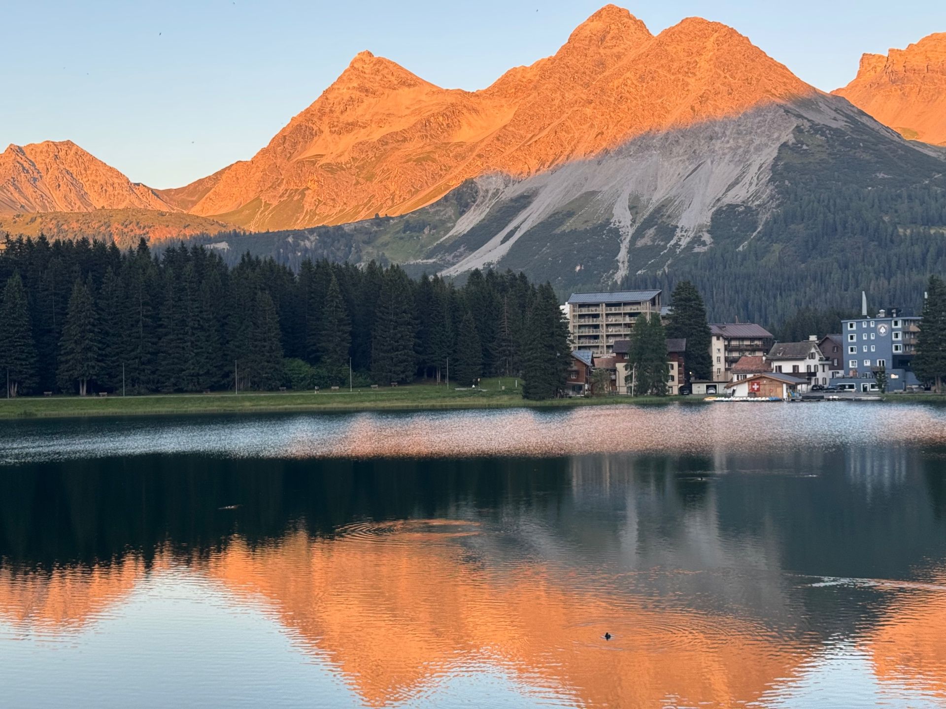 Sunset over the Obersee in Arosa, the peaks glowing orange above the lake