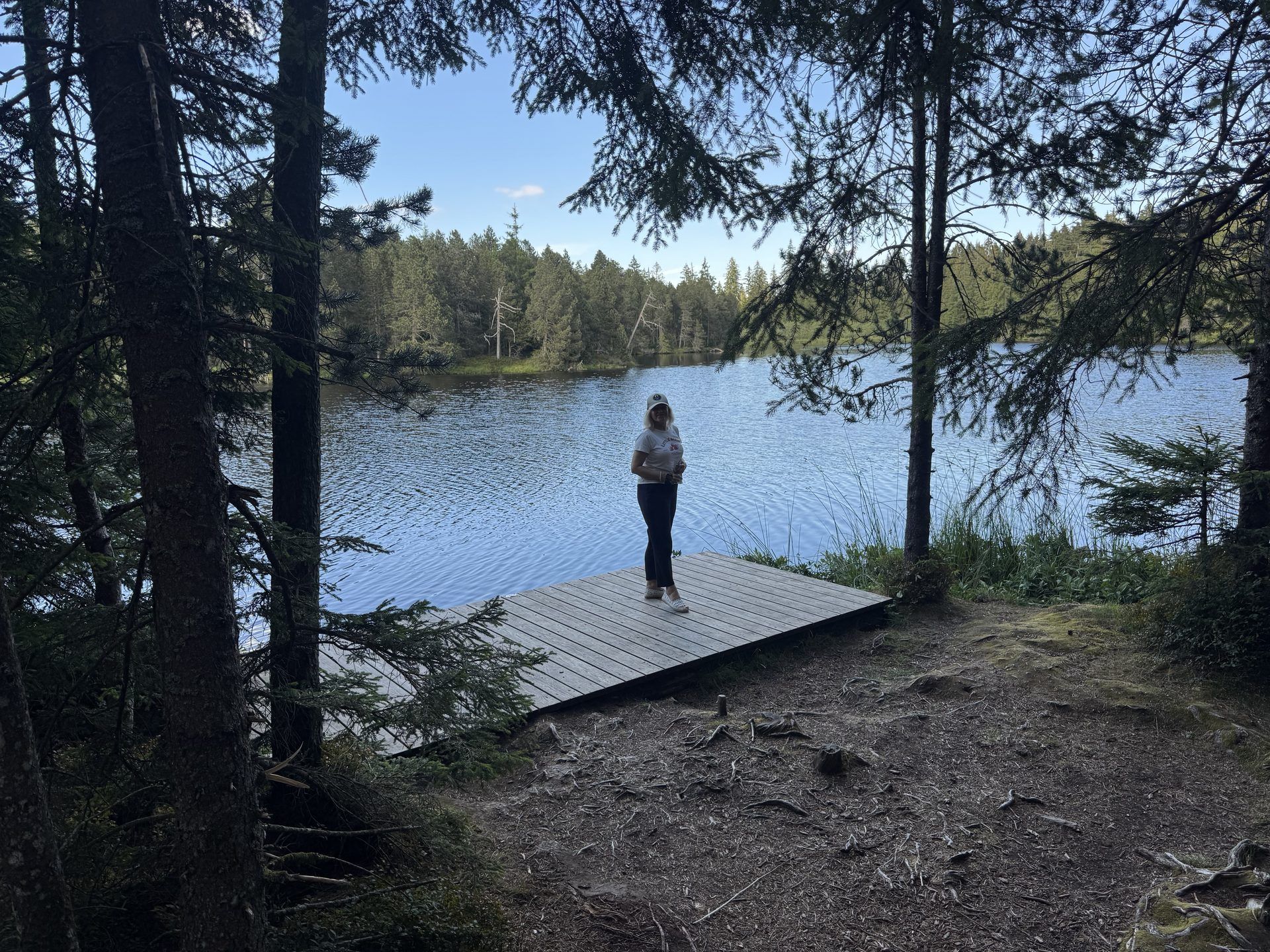 A visitor pausing on a wooden jetty at the water’s edge